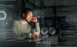 a man in deep thought sat in a dark room working on a laptop - decoration only